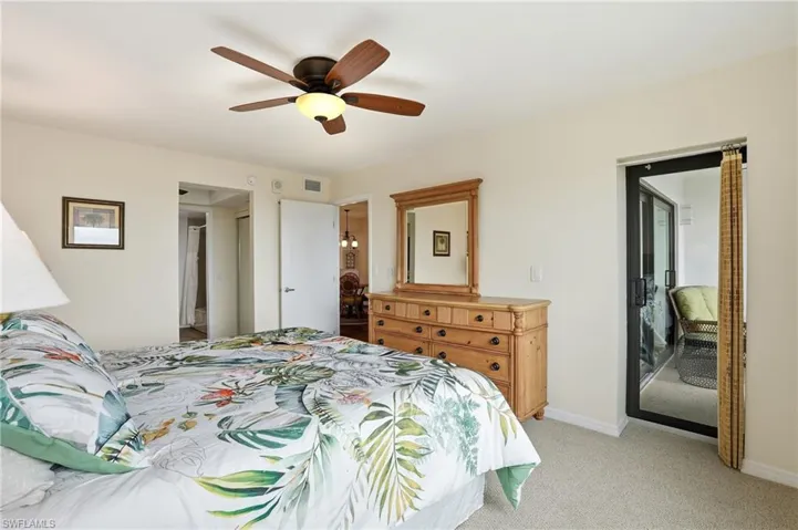 Bedroom featuring light colored carpet and a ceiling fan and patio door to outside screened in balcony - Virtually Edited Image