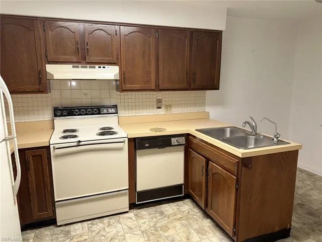 Kitchen featuring white appliances, sink, tasteful backsplash, and light tile floors