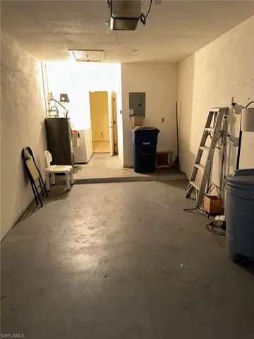 Garage featuring a garage door opener, electric water heater, and washer / clothes dryer