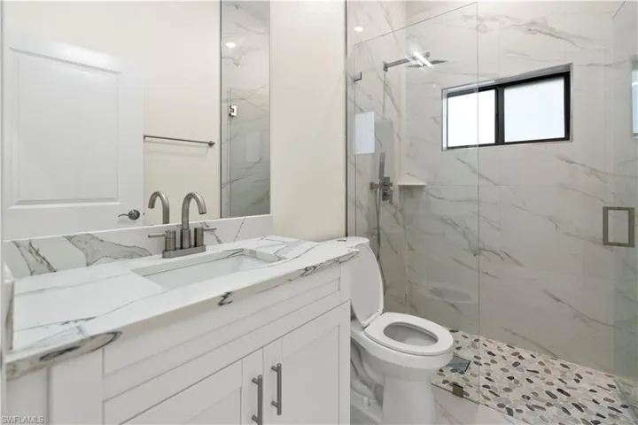 Bathroom with vanity and a marble finish shower