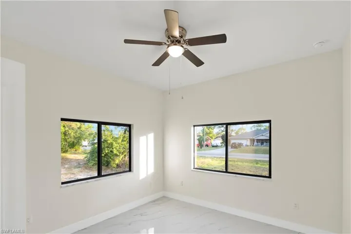 Spare room featuring light marble finish flooring, a ceiling fan, and healthy amount of natural light