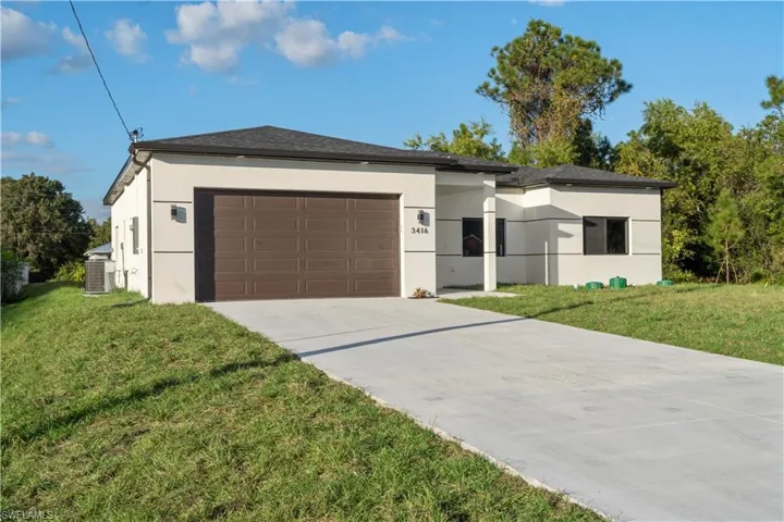 View of front of house with a front lawn, stucco siding, a garage, and concrete driveway