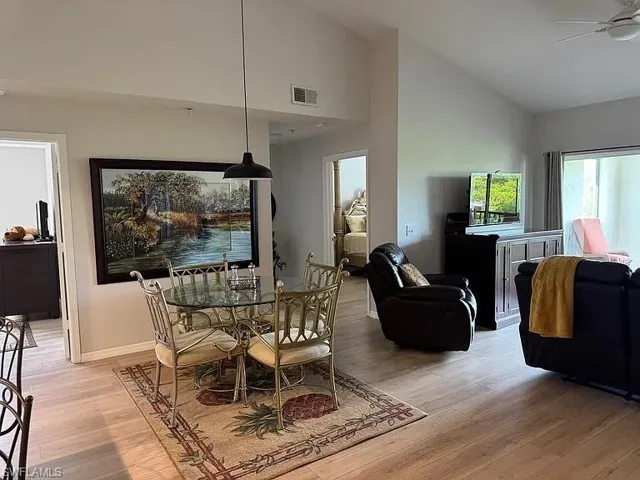 Dining room with light wood finished floors, a ceiling fan, and high vaulted ceiling