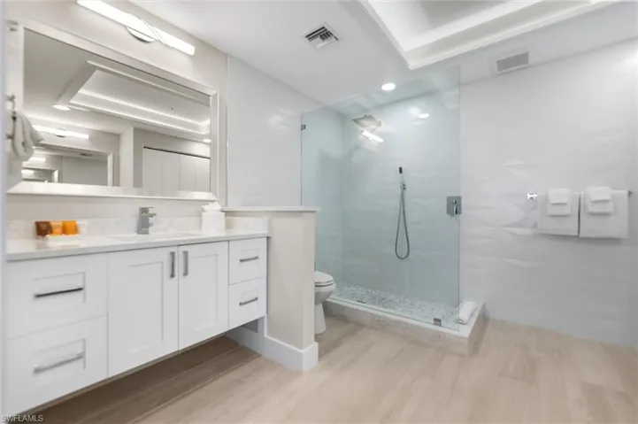 Full bathroom with vanity, walk in shower, and light wood-style flooring