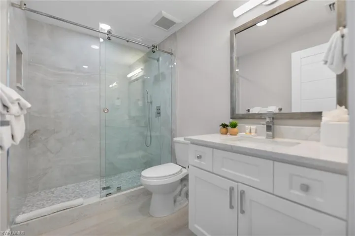 Full bathroom with vanity, a marble finish shower, and light wood-style floors