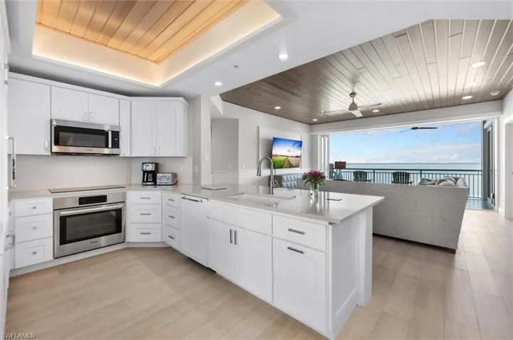 Kitchen featuring a peninsula, wood ceiling, stainless steel appliances, white cabinetry, and open floor plan