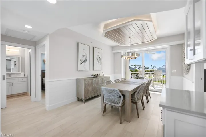 Dining space with a wainscoted wall, light wood finished floors, and suspended lighting
