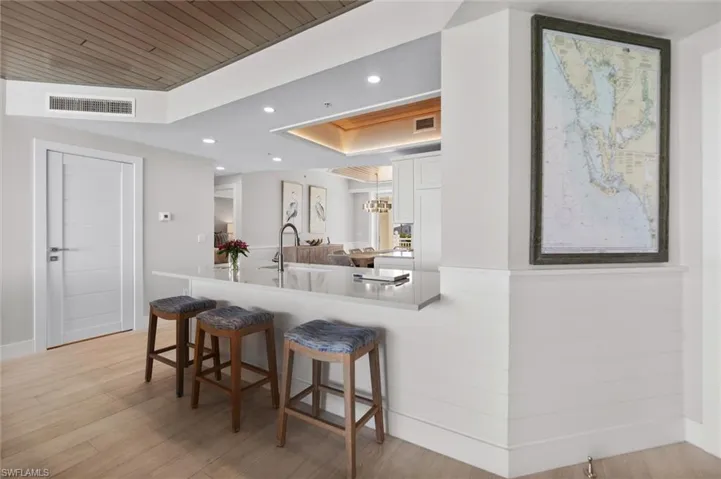 Kitchen with a breakfast bar area, recessed lighting, white cabinets, light wood-style floors, and a peninsula