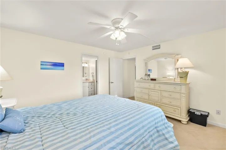 Bedroom with ceiling fan, light carpet, and ensuite bathroom