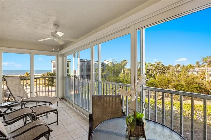 Sunroom featuring tile patterned flooring, a textured ceiling, and a water view
