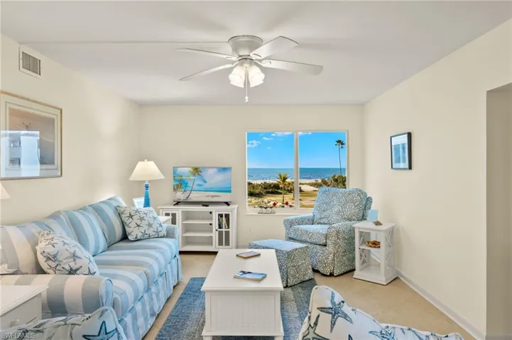 Carpeted living area with ceiling fan and baseboards