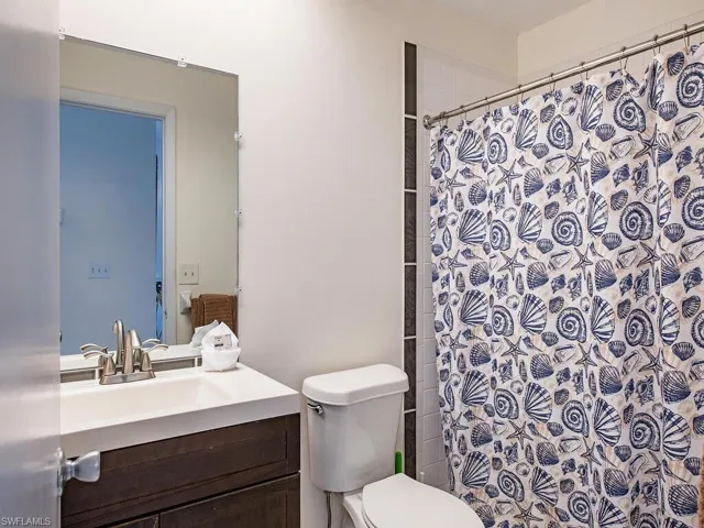 Bathroom with a shower with curtain, vanity, and toilet