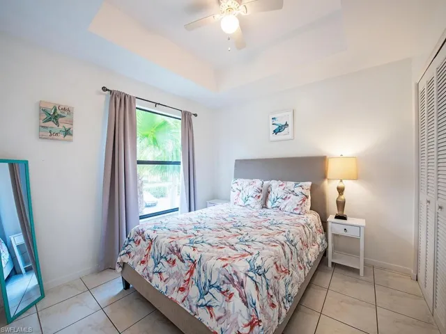 Tiled bedroom featuring a closet, ceiling fan, and a tray ceiling