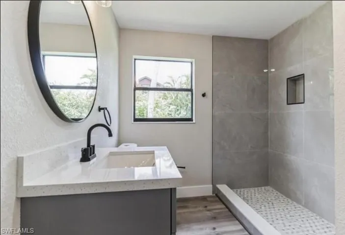 Bathroom with a tile shower, hardwood / wood-style floors, and vanity
