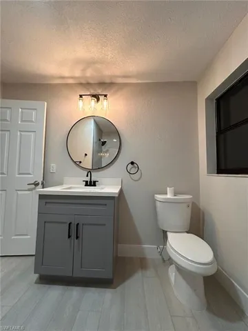 Bathroom with a textured ceiling, vanity, hardwood / wood-style flooring, and toilet