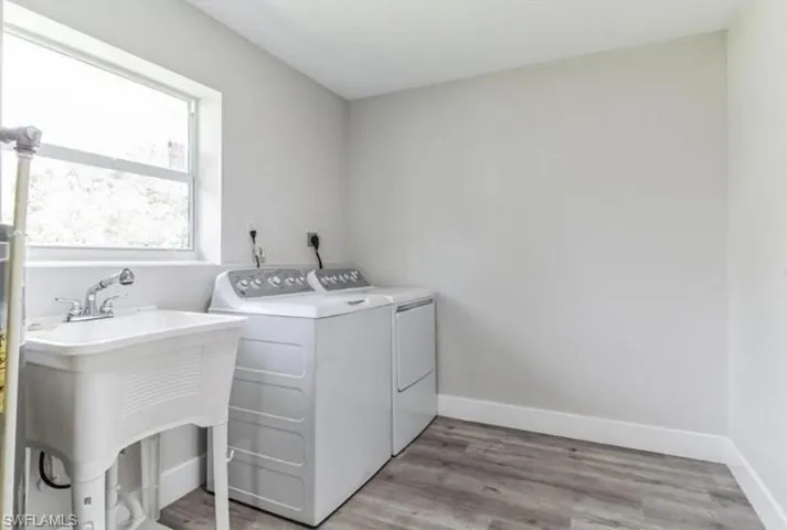 Laundry room featuring separate washer and dryer, sink, and light wood-type flooring