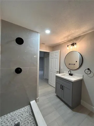 Bathroom featuring vanity, a shower, and a textured ceiling