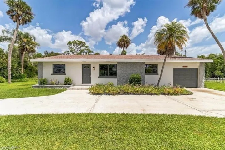 Single story home featuring a garage and a front lawn