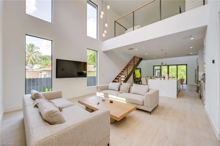 Living area featuring stairs, light wood-type flooring, and a high ceiling