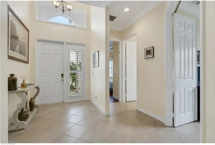 Foyer entrance with hanging lights, crown molding, and light tile patterned flooring