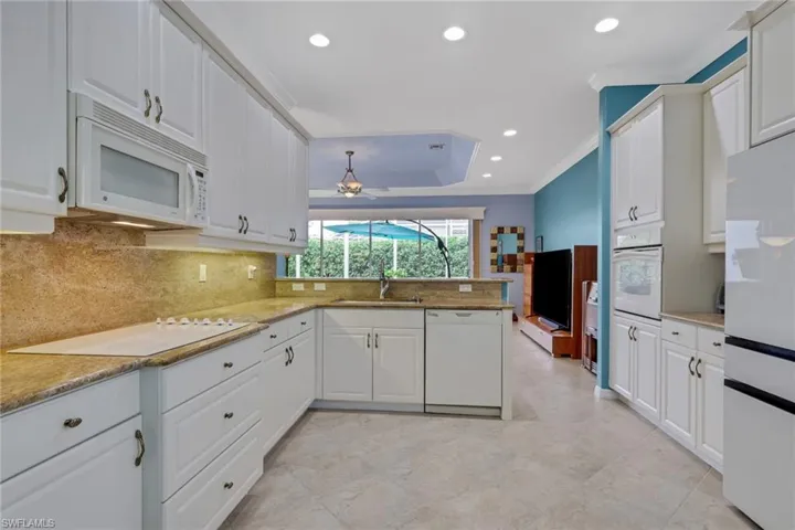 Kitchen with recessed lighting, crown molding, white appliances, white cabinetry, and light stone countertops