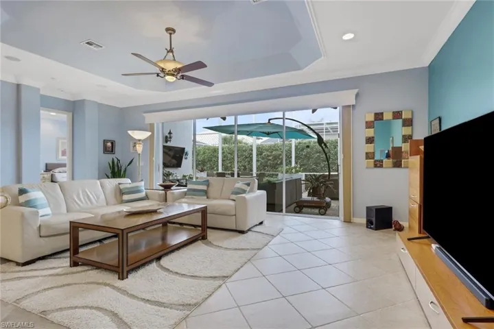 Living area featuring ornamental molding, a sunroom, a raised ceiling, ceiling fan, and light tile patterned flooring