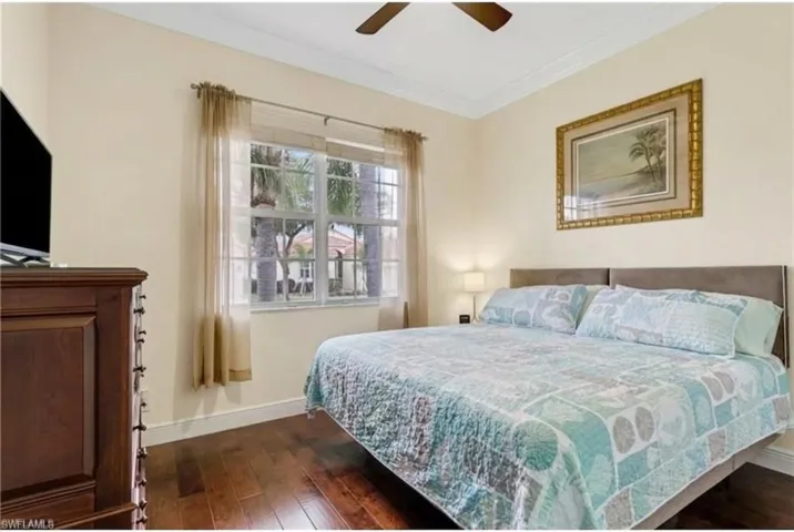 Bedroom featuring dark wood-style flooring, ceiling fan, and ornamental molding