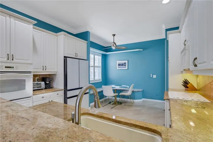 Kitchen featuring white cabinets, white appliances, light stone counters, ceiling fan, and ornamental molding