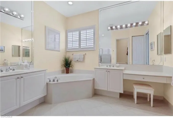 Bathroom with two vanities, light tile patterned floors, and a garden tub
