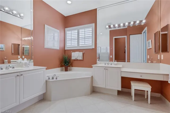 Bathroom featuring two vanities, a bath, and light tile patterned floors