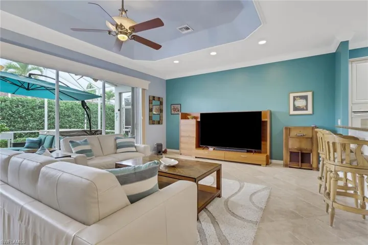 Living area with a ceiling fan, crown molding, recessed lighting, a tray ceiling, and light tile patterned flooring