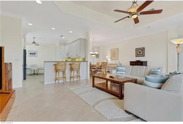 Living room with ceiling fan, recessed lighting, and a raised ceiling