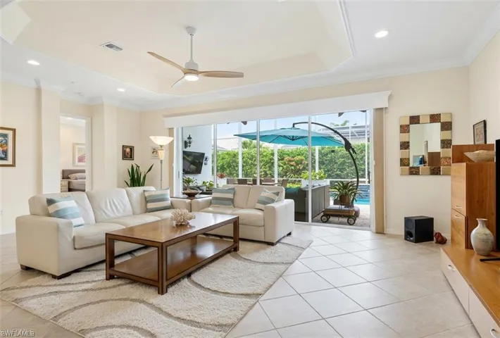 Living area featuring a sunroom, a ceiling fan, crown molding, recessed lighting, and a tray ceiling