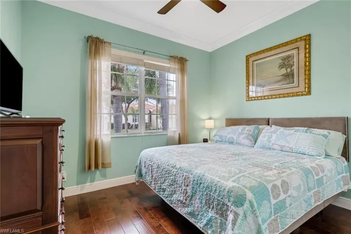 Bedroom featuring dark wood-style floors, crown molding, and ceiling fan