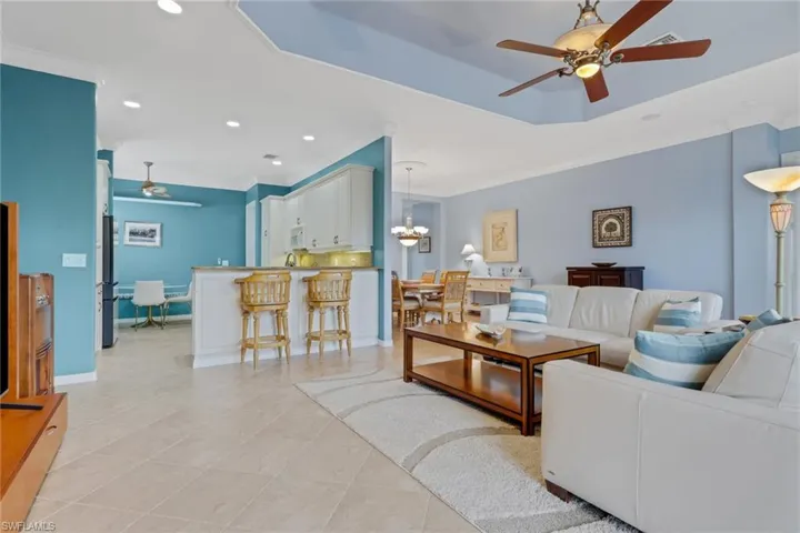 Living area with ceiling fan, a chandelier, recessed lighting, ornamental molding, and light tile patterned floors