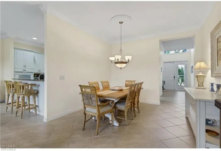 Dining room featuring crown molding, light tile patterned floors, and hanging lights