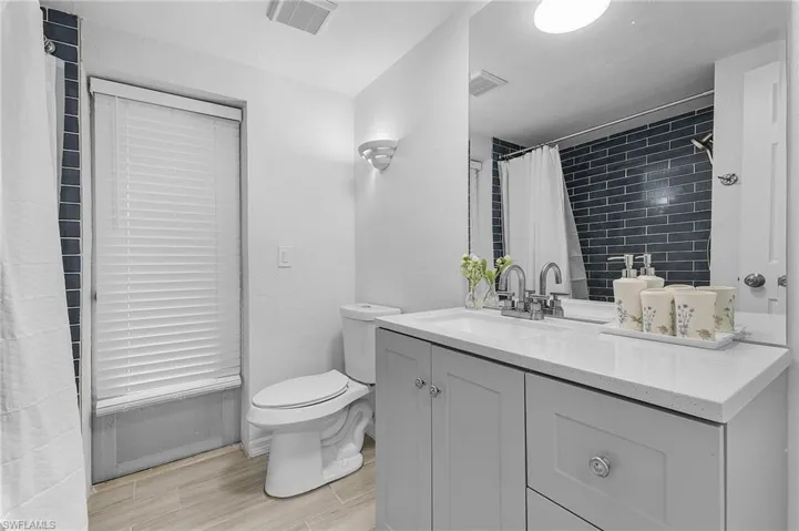 Bathroom featuring a gray vanity with chrome hardware, a white countertop, and a rectangular undermount sink with a chrome faucet