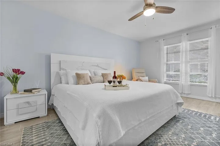 Spacious room featuring light blue walls, wood-finish flooring, and a ceiling fan with integrated lighting