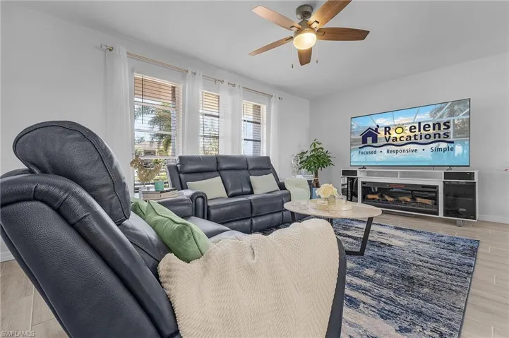 Living area featuring wood-finish flooring, multiple windows with blinds, and a ceiling fan with light fixture
