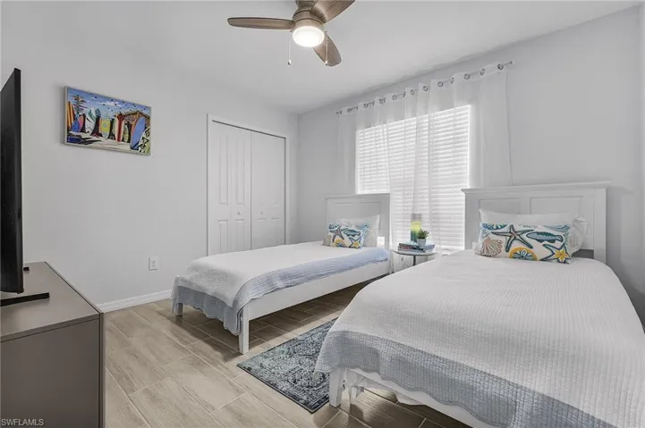 Bedroom featuring wood-look tile flooring, a ceiling fan, and a window with blinds and sheer curtains