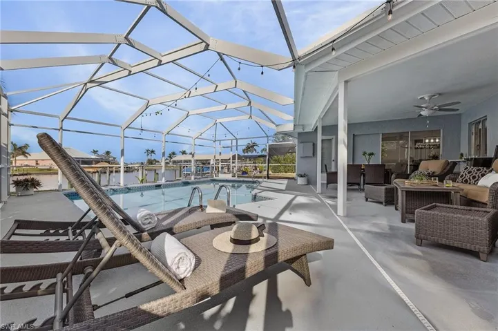 Screened pool enclosure featuring a rectangular swimming pool with integrated lighting, a concrete pool deck, and an expansive covered patio