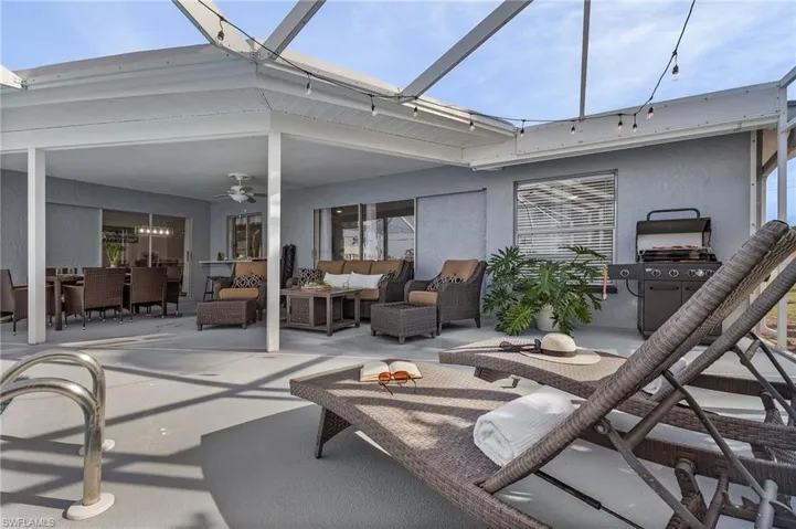 Expansive screened lanai featuring a covered patio, ceiling fan, string lighting, and ample space for dining and lounging