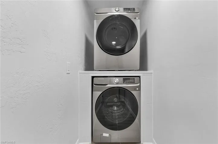 Stackable laundry appliances within a dedicated alcove, featuring a white trim surround