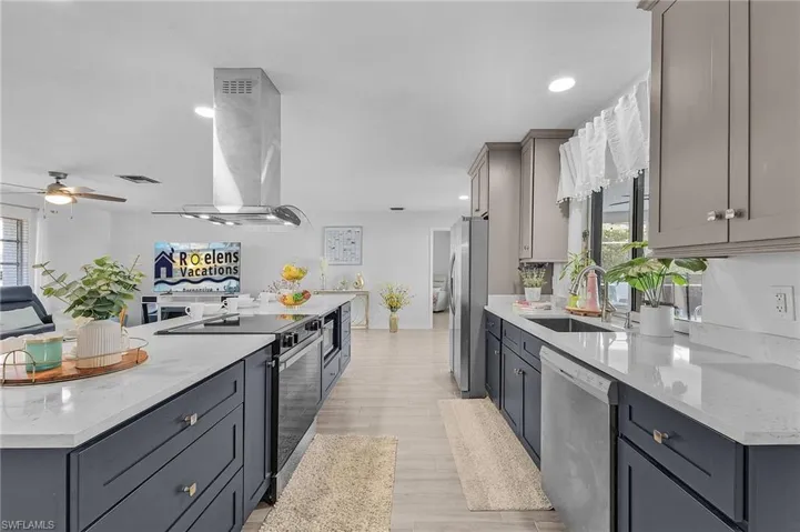Kitchen featuring a central island with an integrated cooktop and overhead range hood