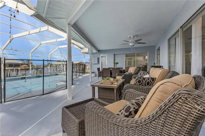 Screened outdoor living area featuring a covered patio, ceiling fan, and pool enclosure