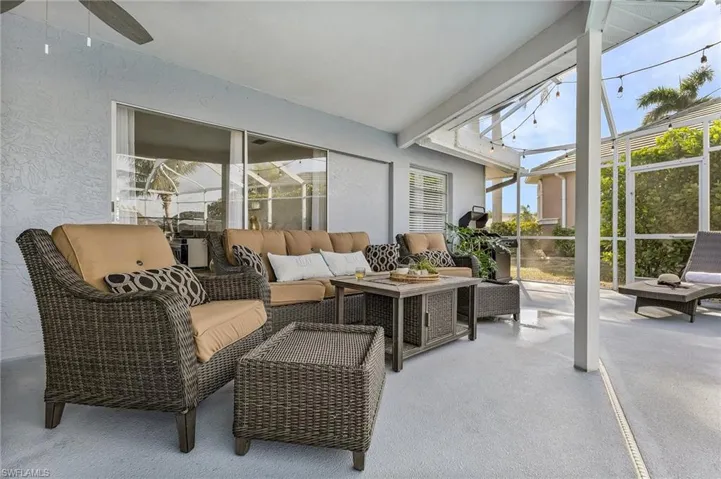 Expansive screened patio featuring a textured concrete floor, a solid roof portion, and a screened enclosure with string lighting
