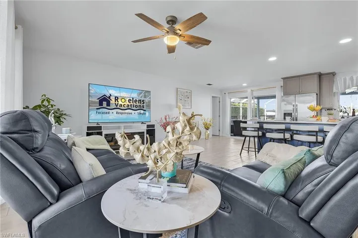 Open-concept living area featuring light-toned tile flooring, recessed lighting, and a ceiling fan