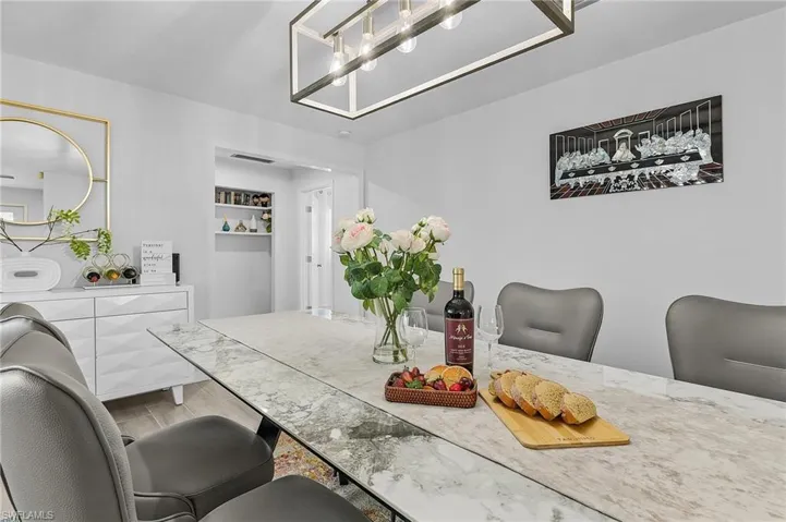 Dining area featuring a rectangular chandelier, a marble-look tabletop, and light gray wall paint