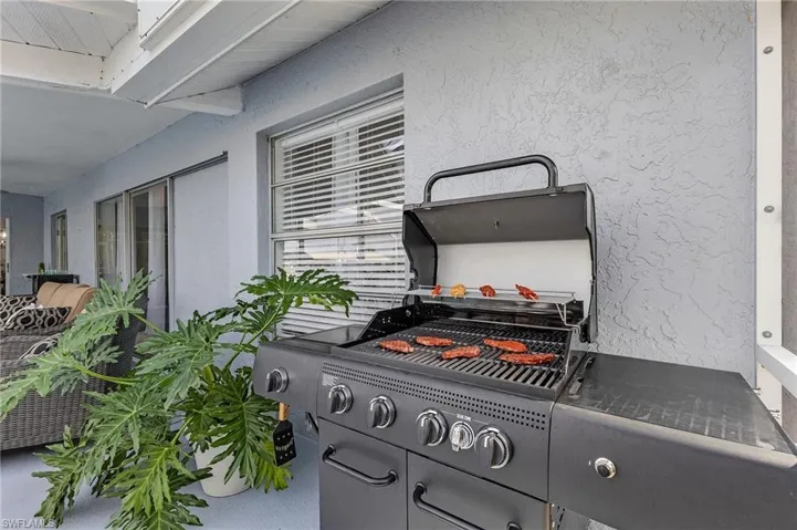 Covered patio featuring a textured stucco exterior, window with horizontal blinds, and large sliding glass doors