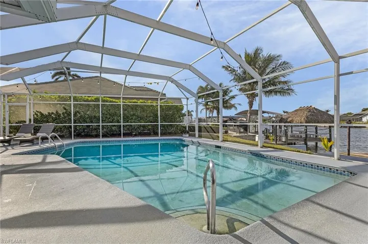 Screened outdoor pool with concrete decking and water feature access